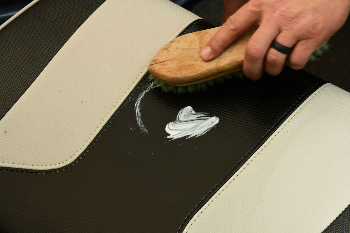 Using a brush to apply Vinyl Conditioner on a boat seat